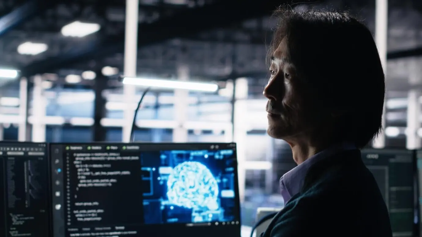 Разработчик программного обеспечения в дата-центре использует компьютер для мониторинга нейросетевого ИИ LLM.